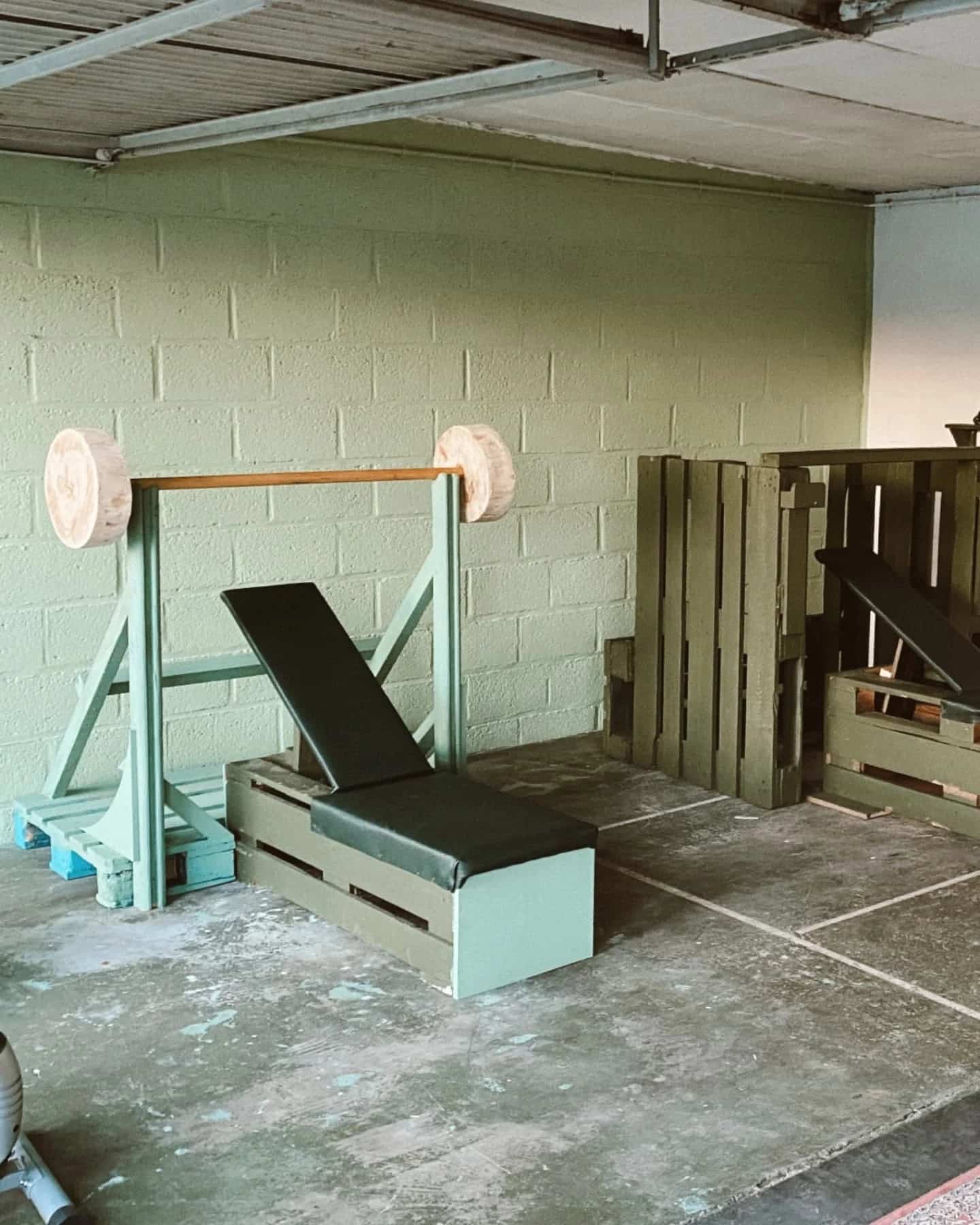 Fitnessruimte met banken en een rek, gebouwd uit pallethout en recuperatiemateriaal.
