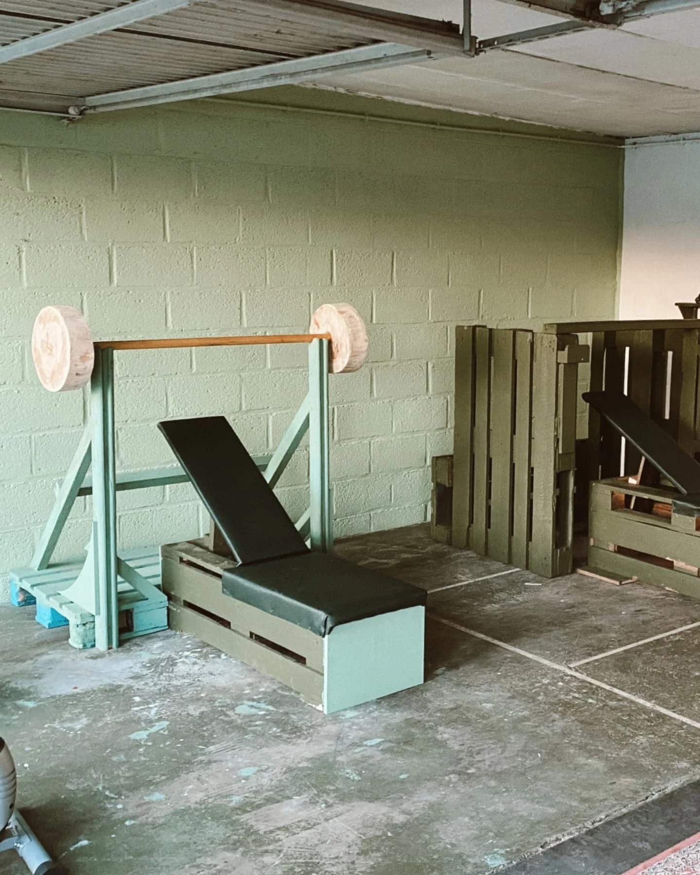 Fitnessruimte met banken en een rek, gebouwd uit pallethout en recuperatiemateriaal.
