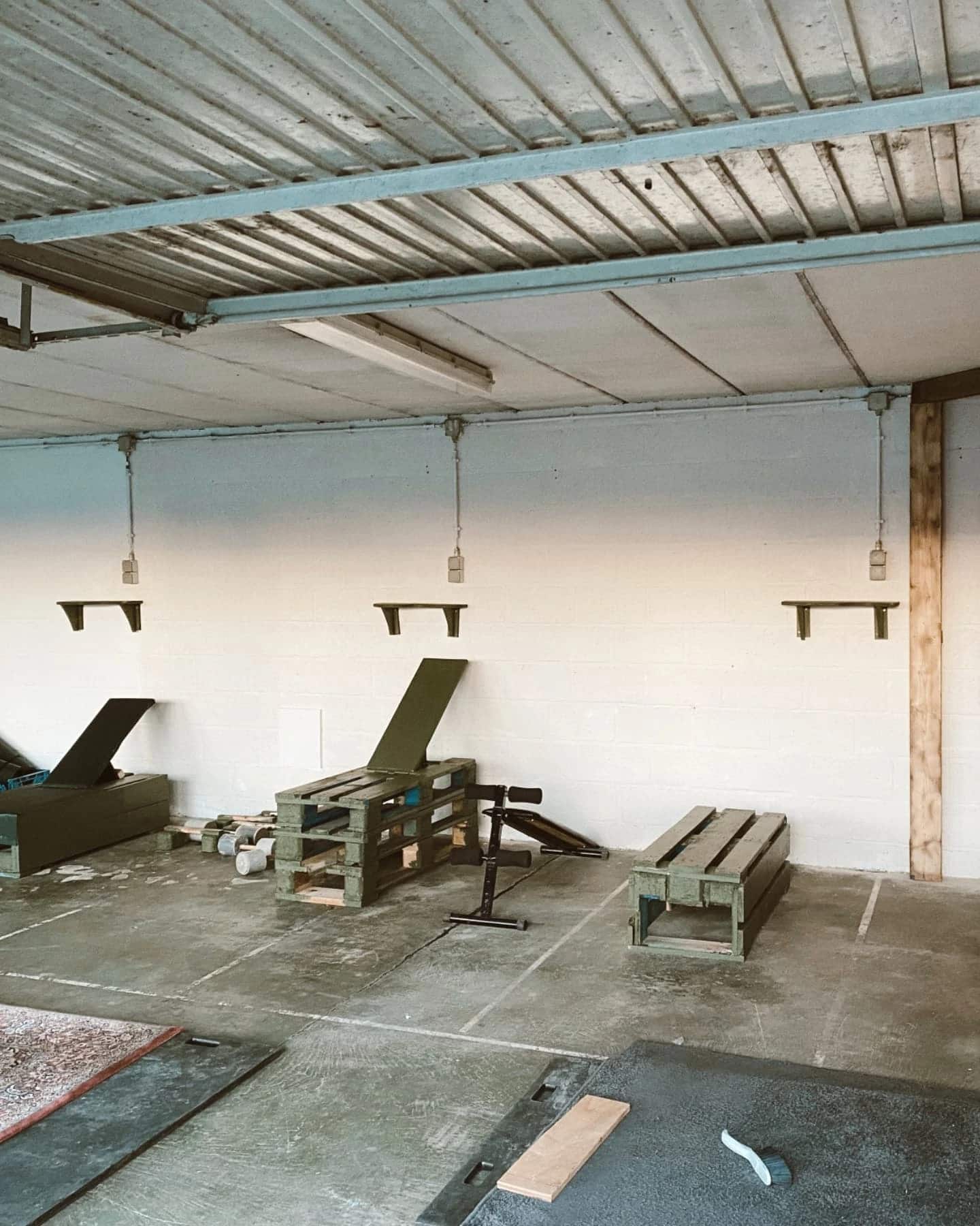 De afgewerkte fitnessruimte met zelfgemaakte banken uit hout.