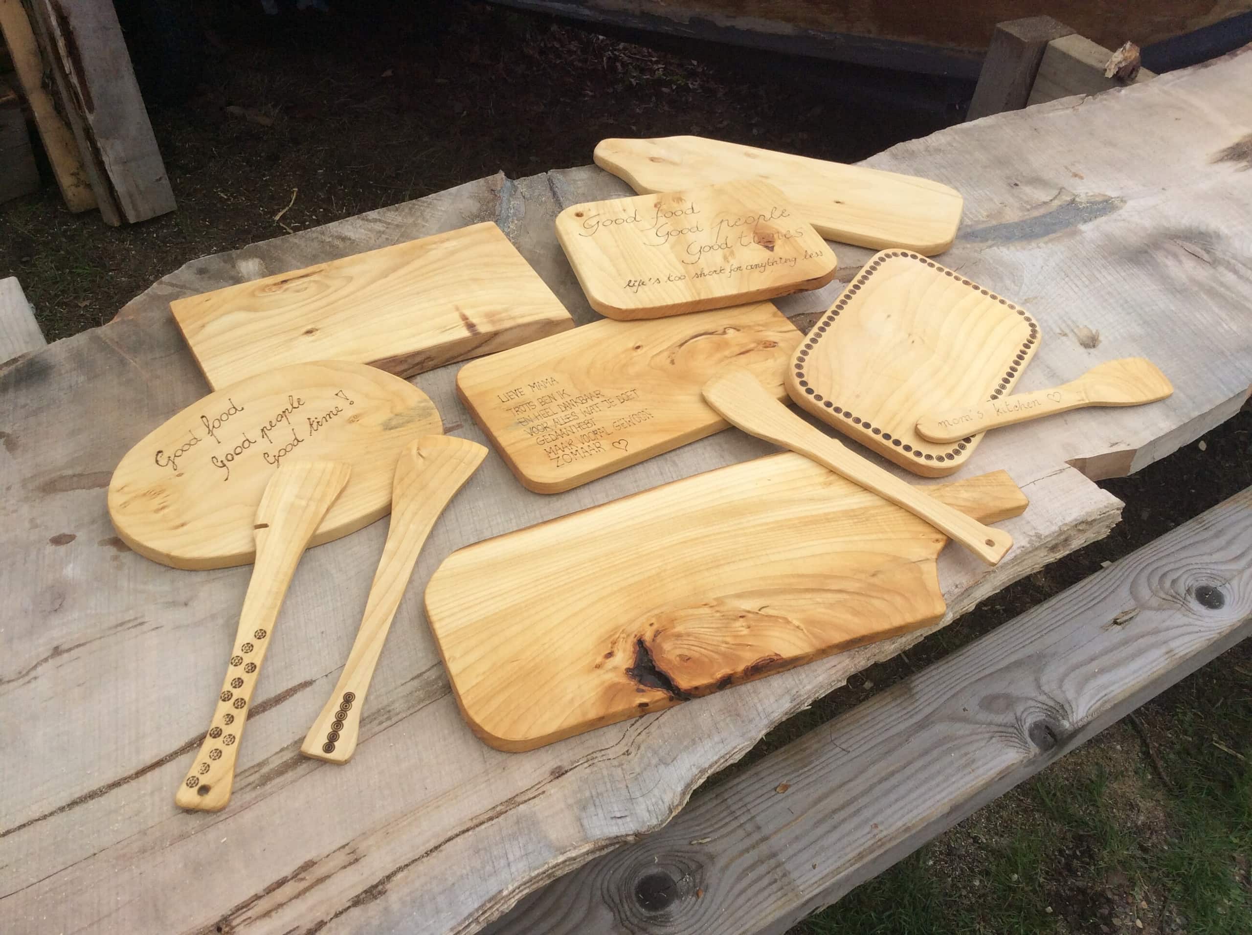 Plankjes en spatels met ingebrande tekst, uitgestald op een houten tafel.