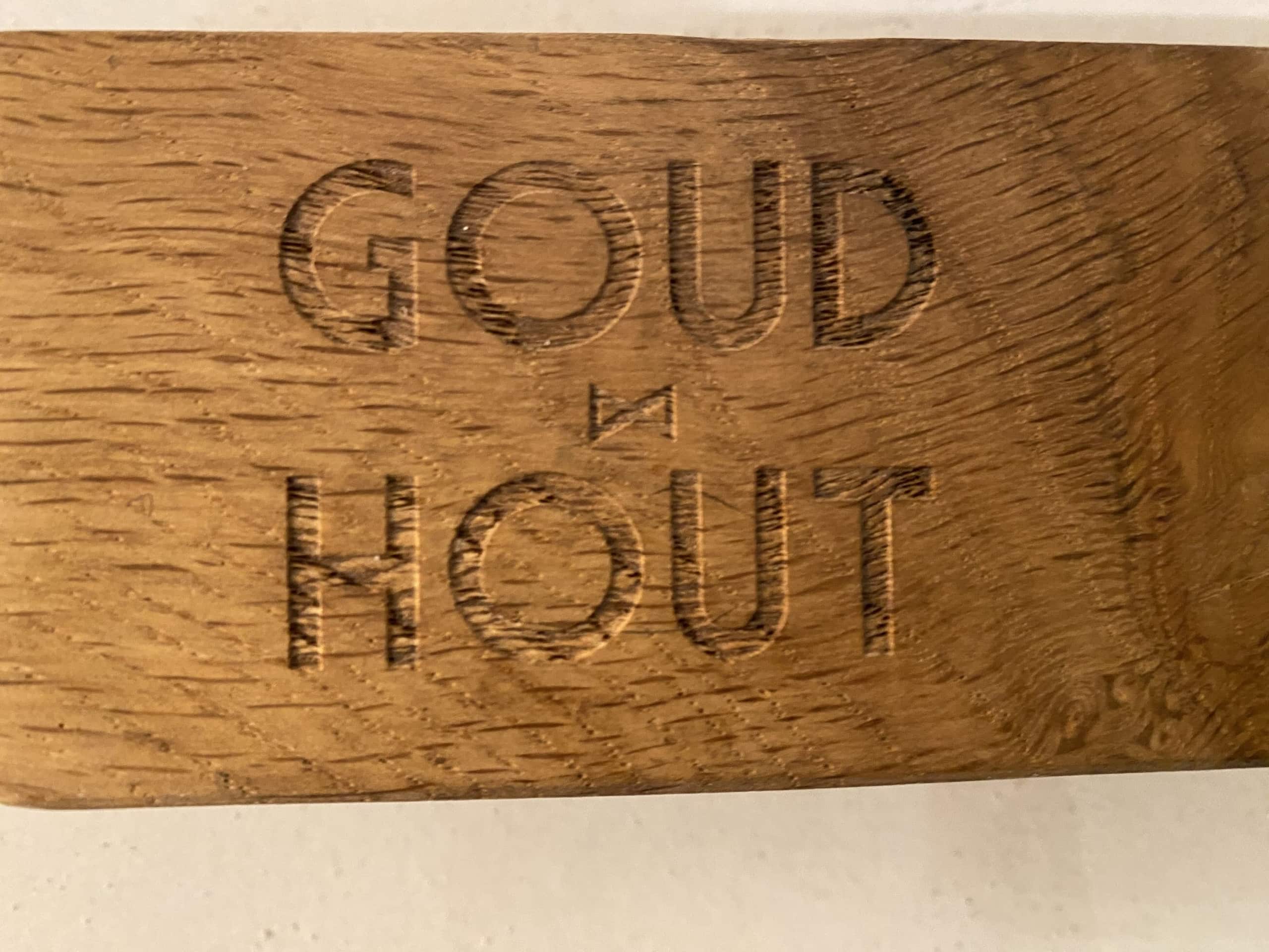 De woorden GOUD IN HOUT, ingebrand in een geoliede eiken plank.