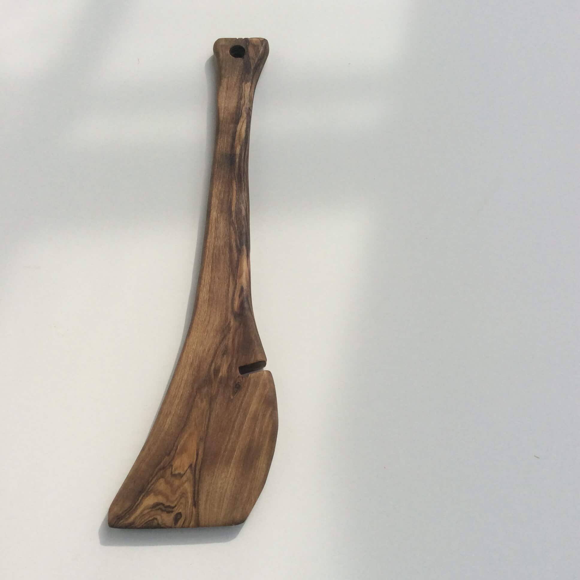 Een uit één stuk gesneden houten hakmes aan een witte muur, met de nerf in de lengte.