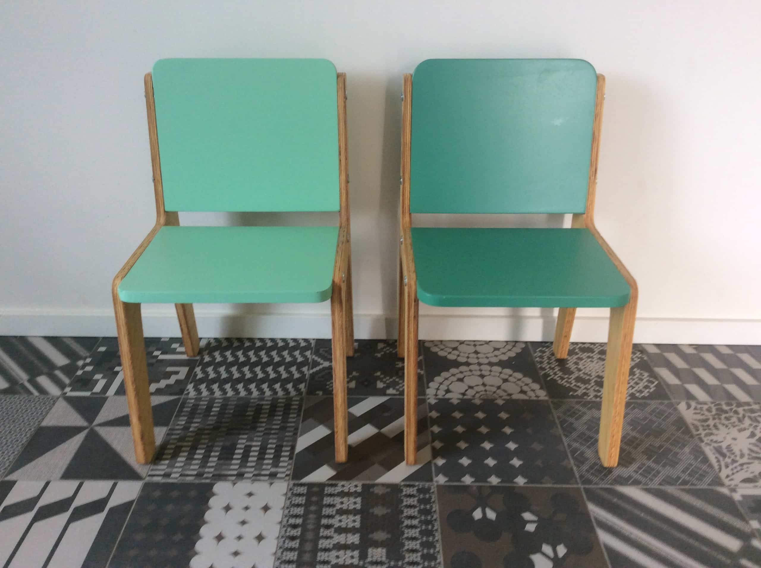 Twee stoelen naast elkaar met houten onderstel en een zitting en rugleuning in zachtgroen.